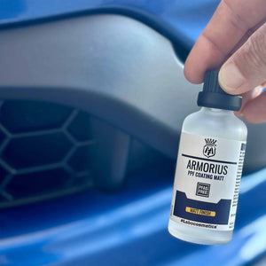 Bottle of Armorius PPF Coating Matt held by a hand with a blue car in the background