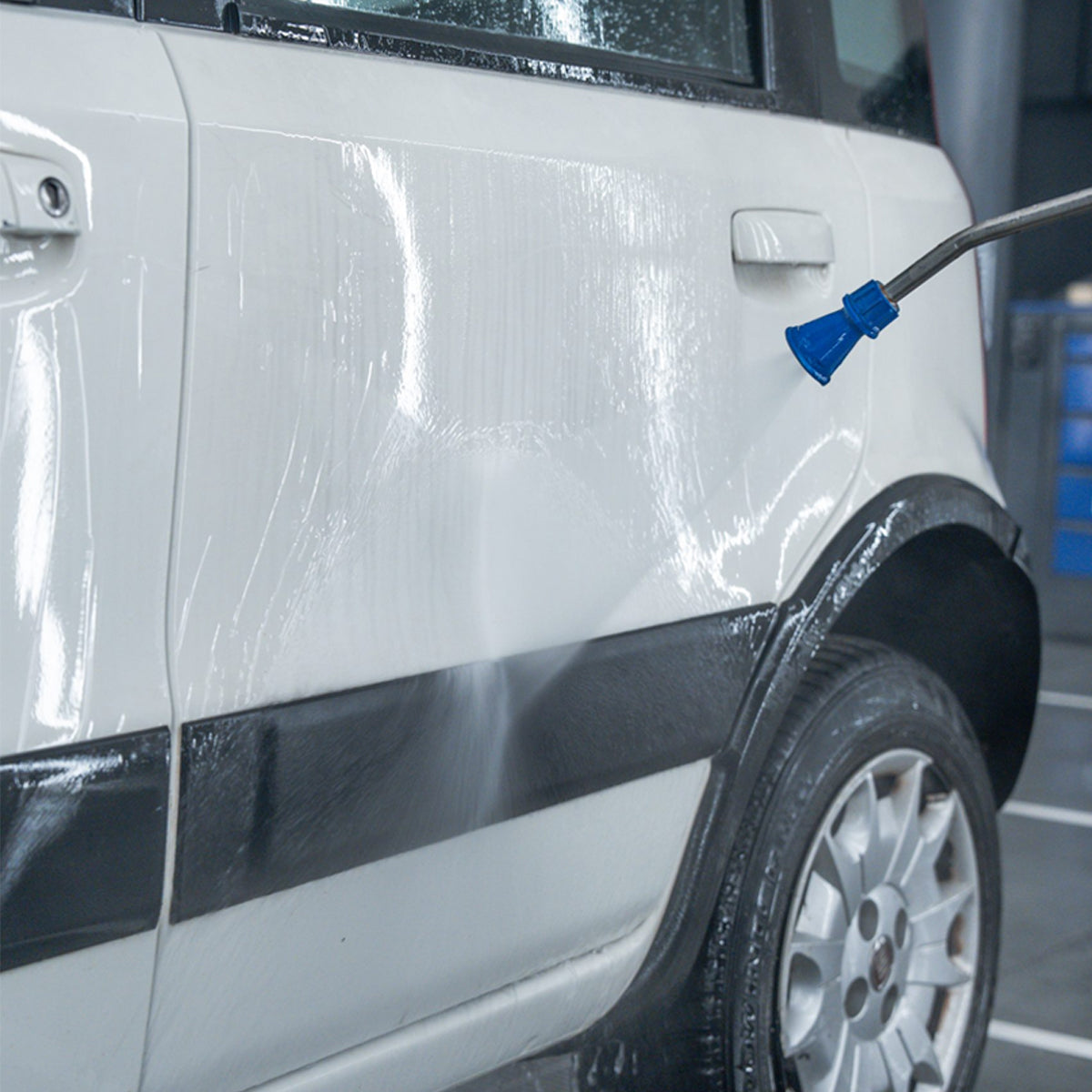 Car being washed with a high-pressure water gun on a wet surface