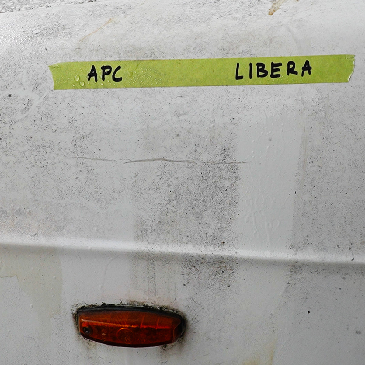 White surface with green tape labeled 'APC' and 'LIBERA', and a red light below.