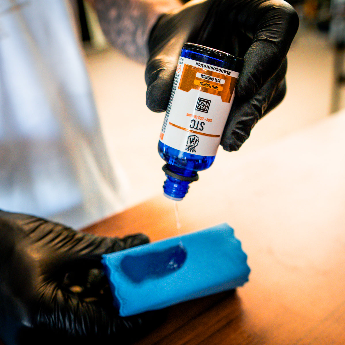 Person applying blue ink to a tattoo with a bottle and blue sponge.