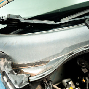 Car windshield with wipers and a damaged area on the hood