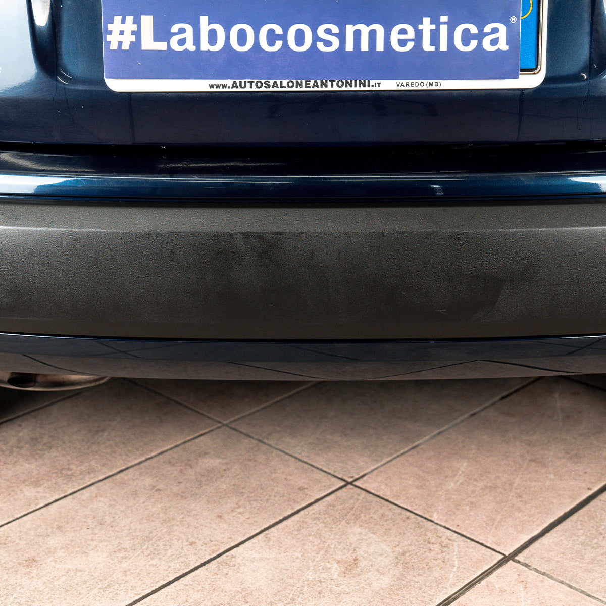 Car bumper with a #Labocosmetica sticker on a tiled floor