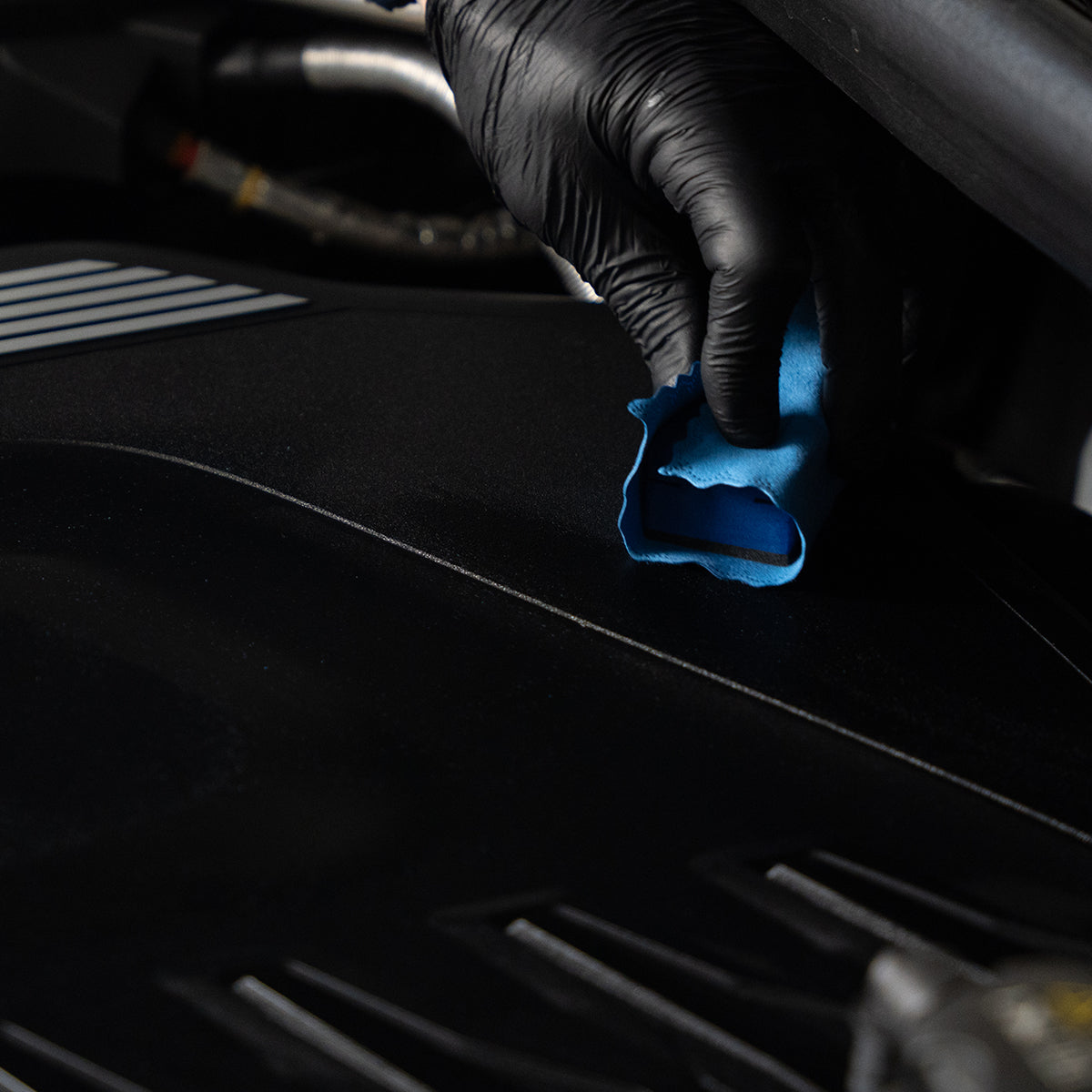 Person cleaning car interior with a blue cloth and black gloves