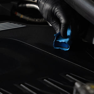 Person cleaning car interior with a blue cloth and black gloves