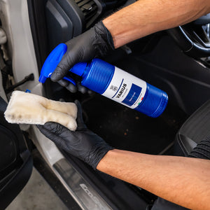 Person cleaning car interior with a spray bottle labeled 'Varius' and a cloth.