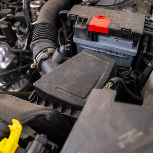 Close-up of a car battery and surrounding engine components.