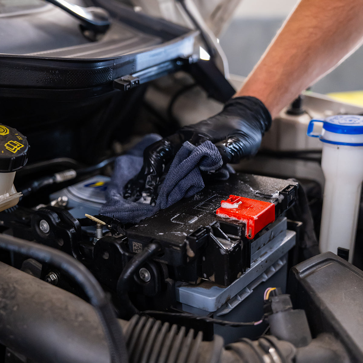 Person working on a car battery with gloves on