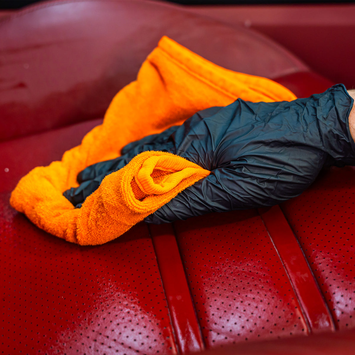 Orange and black microfiber cloths on a red leather surface