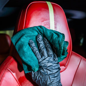Green towel and black glove on a red car seat