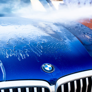 Close-up of a blue BMW car with water droplets on the hood.