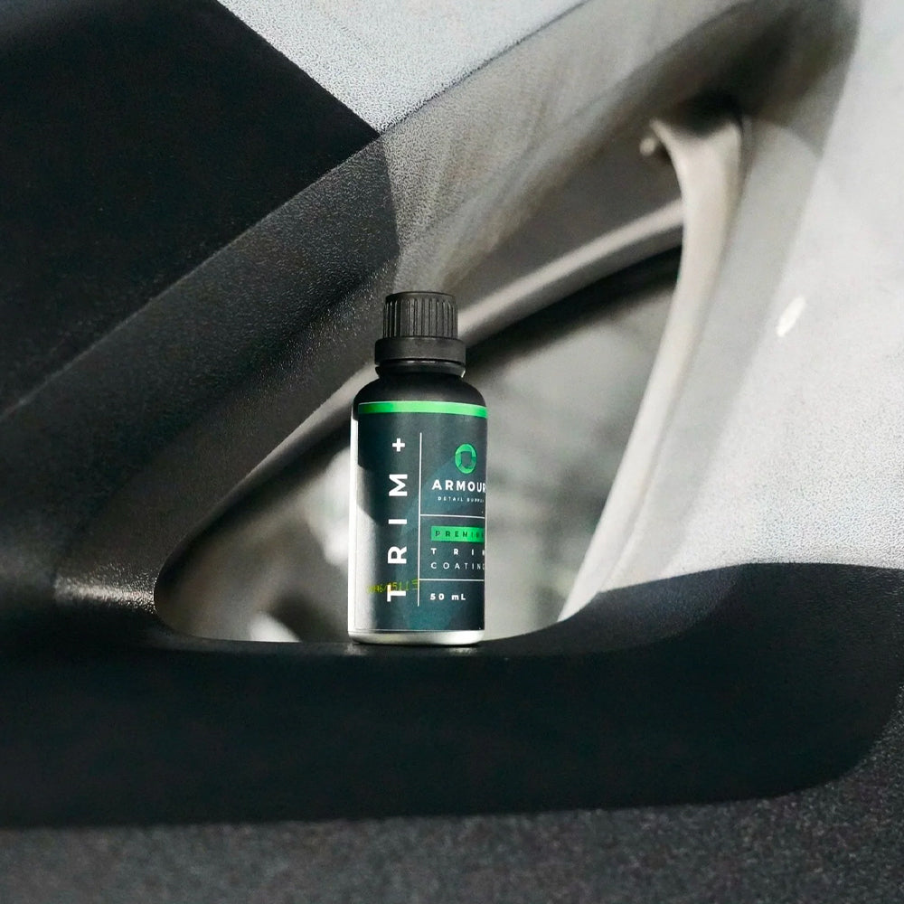 Bottle of Trim+ Armour sitting inside a car's cup holder.