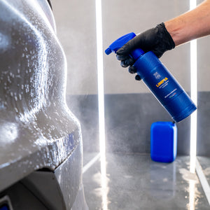 Person using a blue spray bottle labeled 'Liqui Moly' to clean a car.