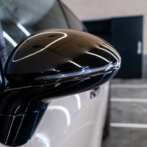 Close-up of a car's black side mirror with a blurred background