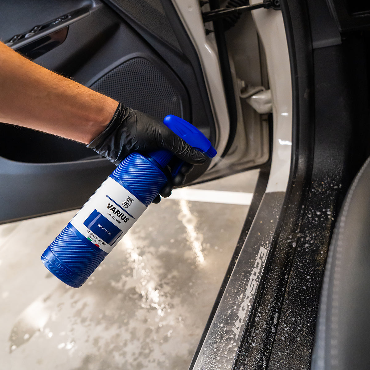 Person cleaning car interior with a spray bottle labeled 'Varius'.