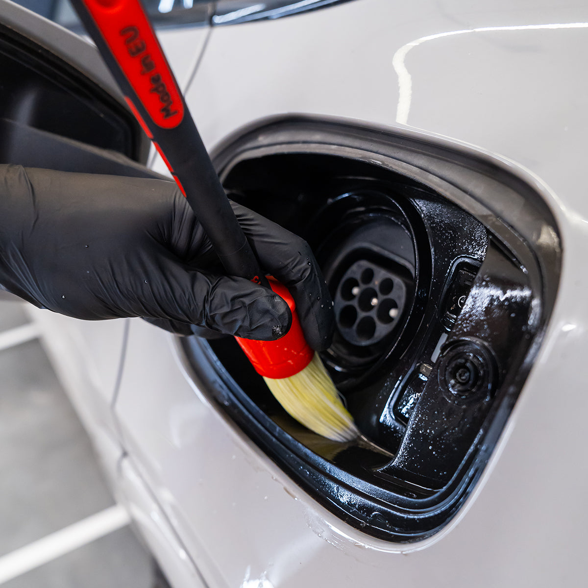 Cleaning a car's charging port with a brush and black glove