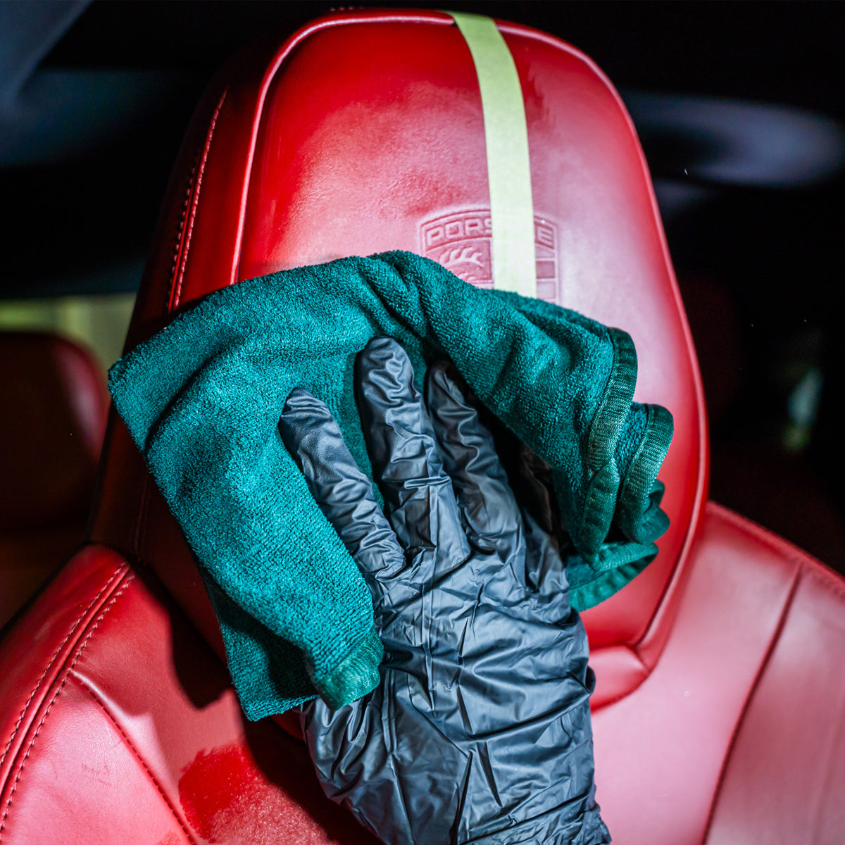 Green towel and black glove on a red car seat