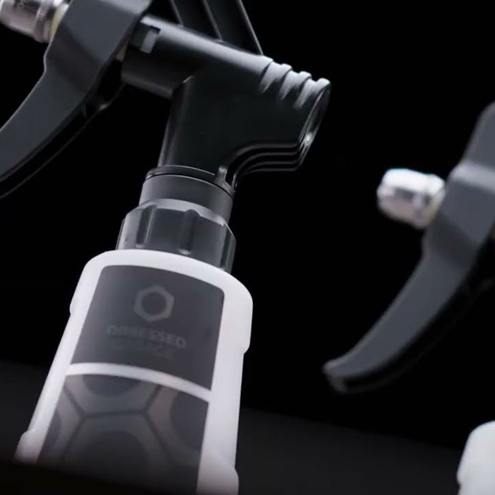 Close-up of a spray trigger with a brand logo on a black background