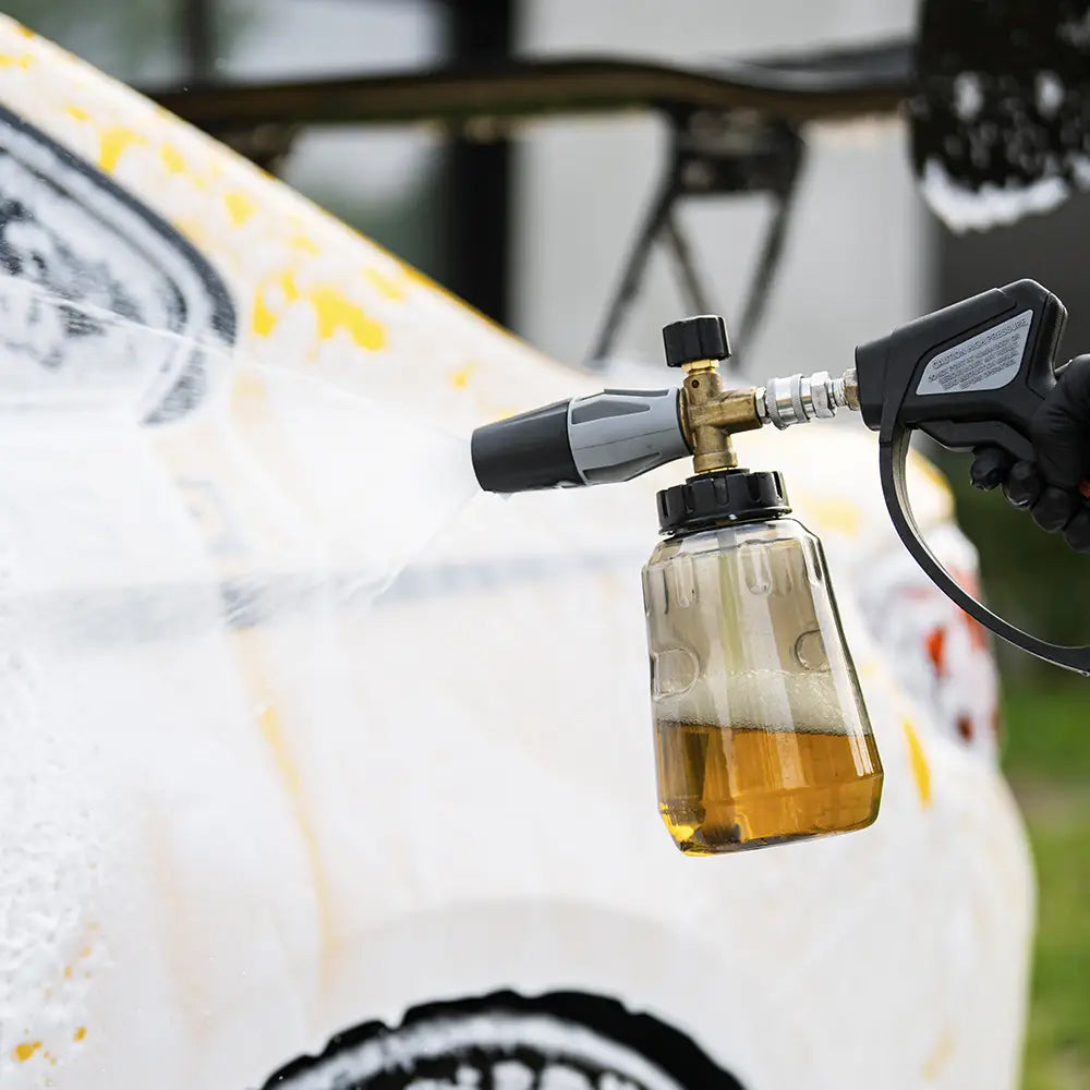 Foam cannon attached to a pressure washer with a surfboard in the background