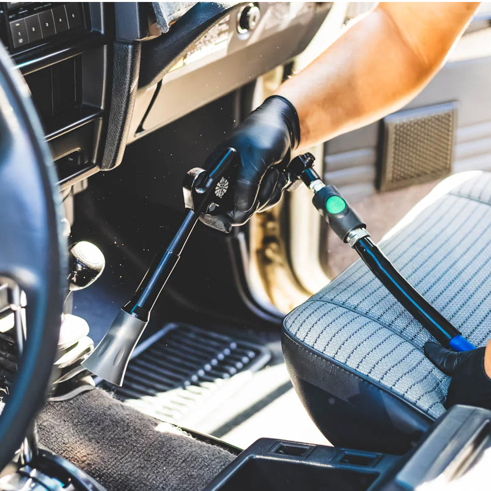 Person using a tool inside a vehicle, likely for maintenance or repair.